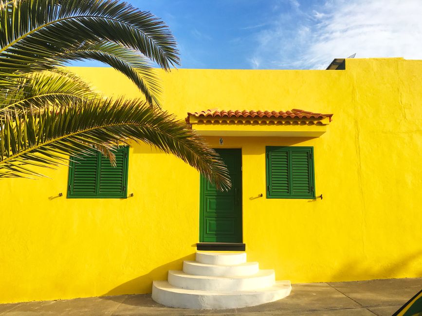 Yellow painted house wall with green shutters